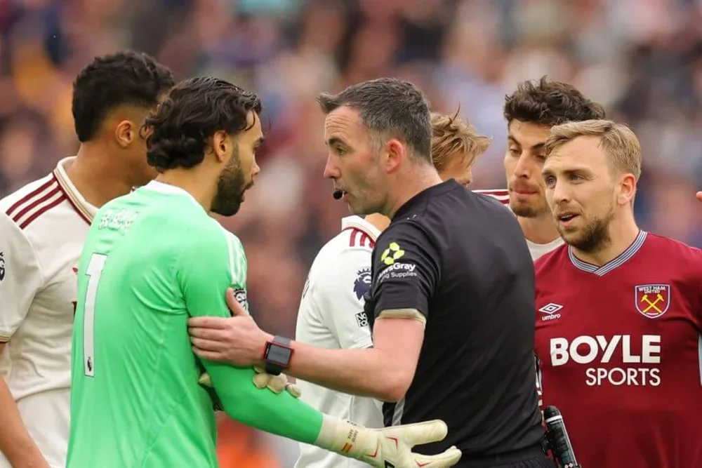 Jarrod Bowen (furthest right) talks with referee Chris Kavanagh (centre, wearing black) and Arsenal goalkeeper David Raya (left, wearing green) while a VAR review is ongoing